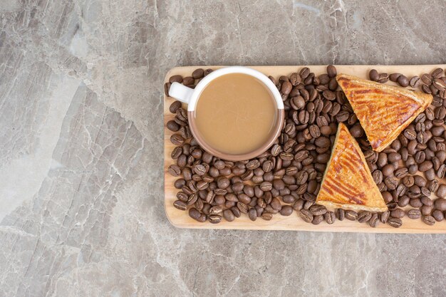 Taza de café, galletas y granos de café sobre tabla de madera. Foto de alta calidad