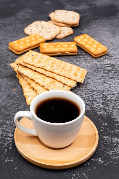 taza de café con galletas en la mesa oscura
