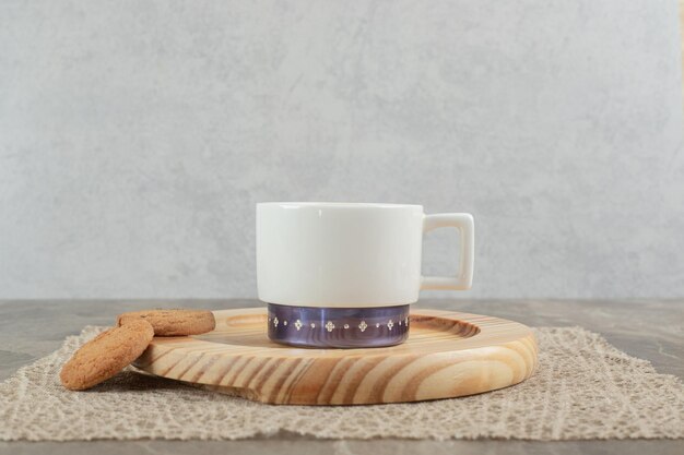 Taza de café y galletas en placa de madera