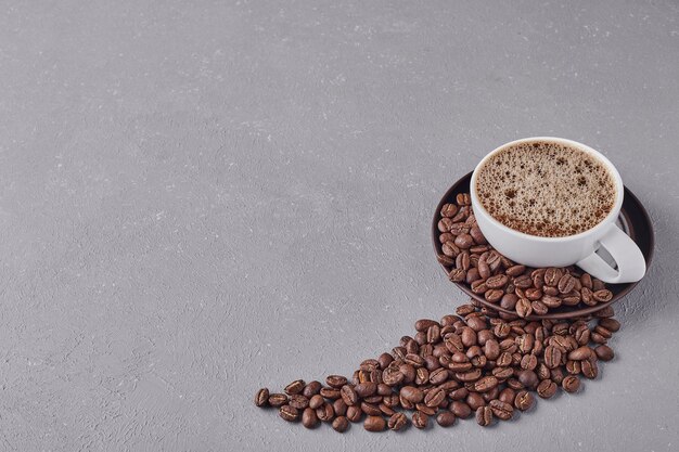 Una taza de café con granos de arábica alrededor.