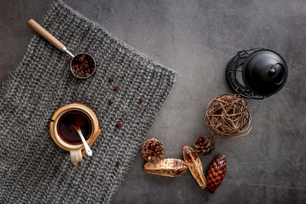 Taza de café con granos de café en una bufanda de punto gris