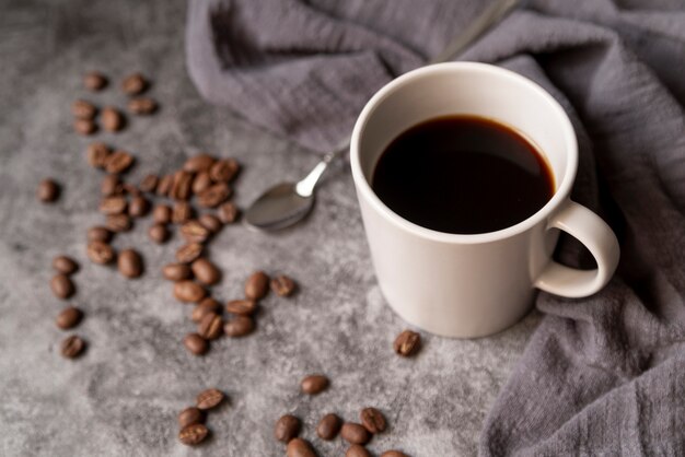 Taza de café con granos de café y cuchara.