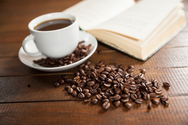 Taza de café con granos de café y el libro