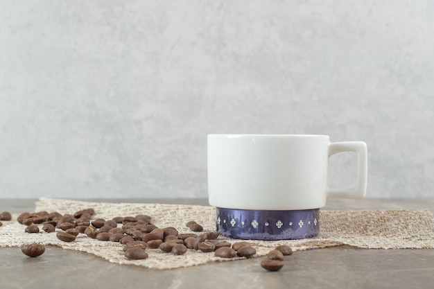 Taza de café y granos de café en la mesa de mármol.