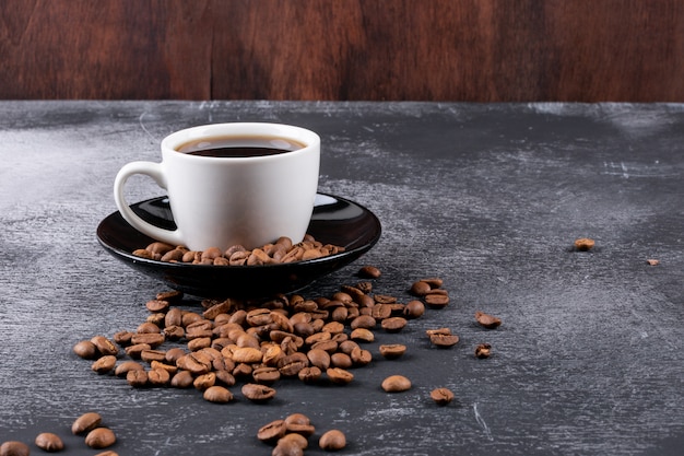 Taza de café con granos de café en la mesa oscura