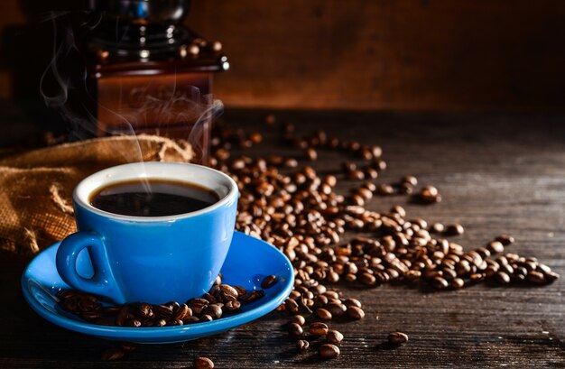 Taza de café con granos de café y molinillo de fondo