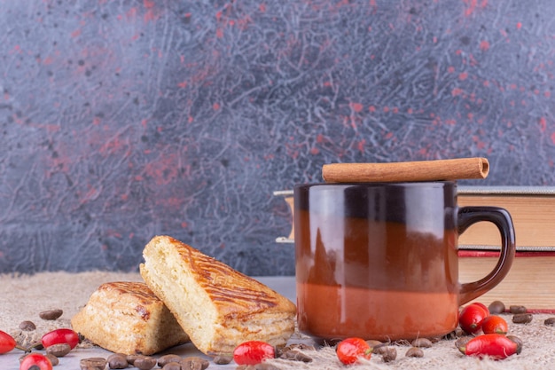 Taza de café con granos de café y pasteles sobre arpillera. Foto de alta calidad