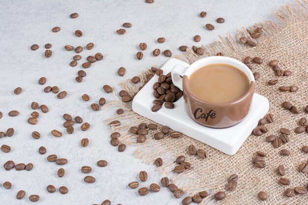 Taza de café y granos de café sobre arpillera. Foto de alta calidad