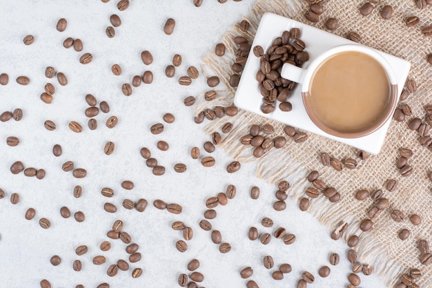 Taza de café y granos de café sobre arpillera. Foto de alta calidad