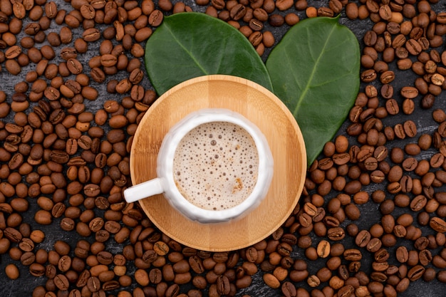 Taza de café y granos de café en la vista superior de superficie negra