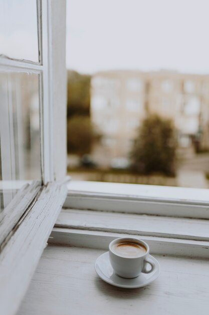 Una taza de café junto a la ventana.