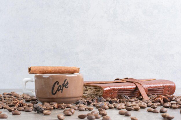 Taza de café con leche con granos de café y cuaderno. Foto de alta calidad