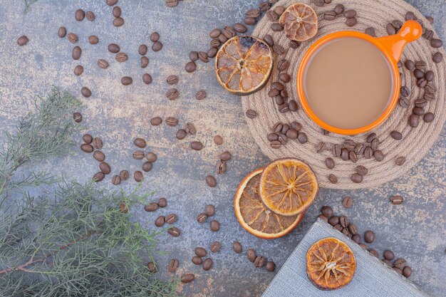 Taza de café con leche con granos de café y naranjas. Foto de alta calidad