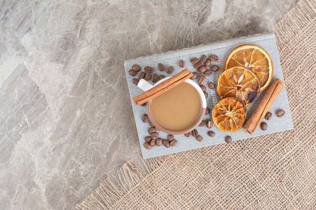 Taza de café con leche con granos de café y rodajas de naranja en el libro. Foto de alta calidad