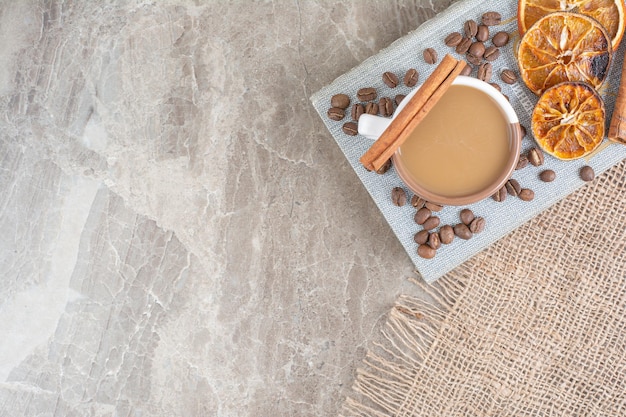 Taza de café con leche con granos de café y rodajas de naranja en el libro.