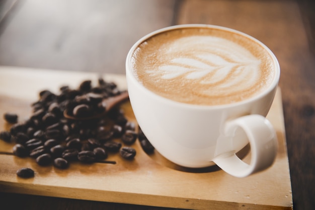 Taza de café con leche en la mesa de madera en cafetería cafetería