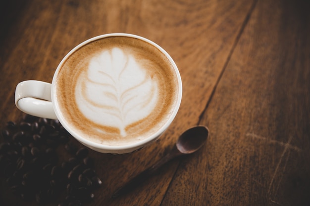 Taza de café con leche en la mesa de madera en cafetería cafetería