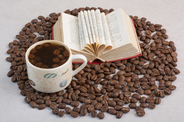 Una taza de café con libros y granos de café sobre fondo blanco. Foto de alta calidad