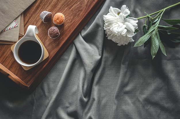 Taza de café y magdalenas en una bandeja en la cama, desayuno plano en la cama