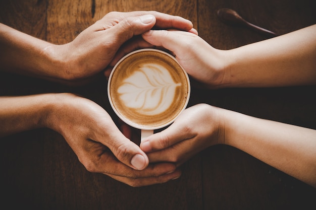 Una taza de café en manos de un hombre y una mujer. Enfoque selectivo