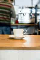 Foto gratuita taza de café en la mesa de madera sobre fondo de cafetería defocused