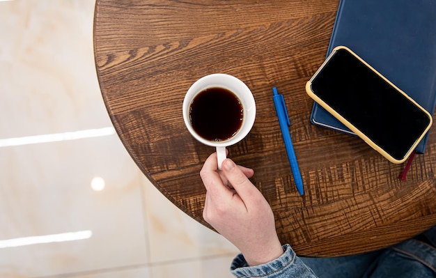 Una taza de café en una mesa de madera y una vista superior de la libreta