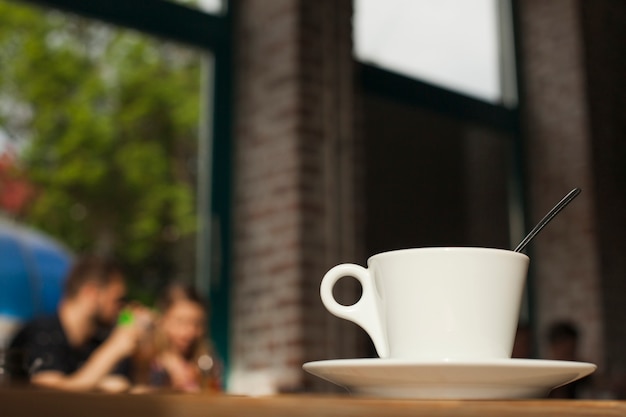 Taza de café en la mesa sobre fondo de cafetería defocused