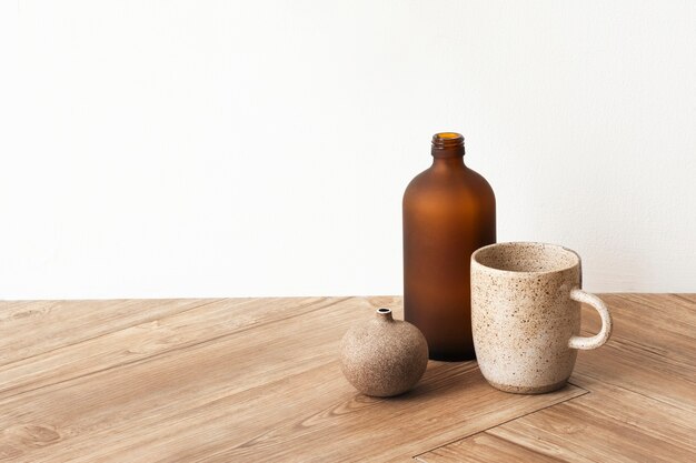 Taza de café mínima por un jarrón marrón sobre un piso de madera