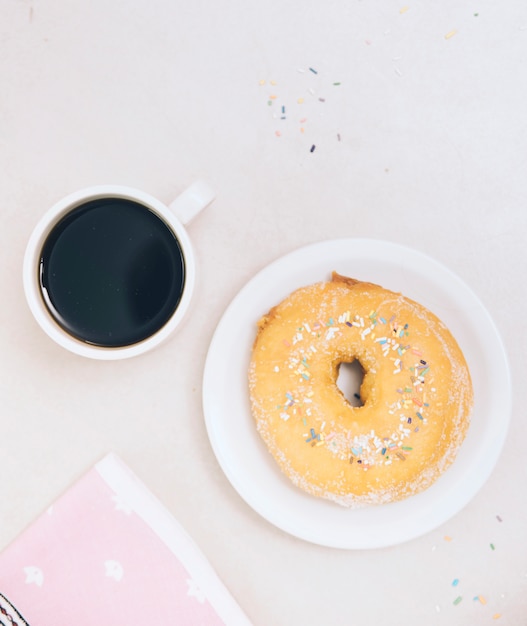 Foto gratuita taza de café negro; donut entero y servilleta sobre fondo blanco