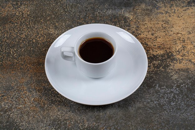 Taza de café negro sobre la superficie de mármol.