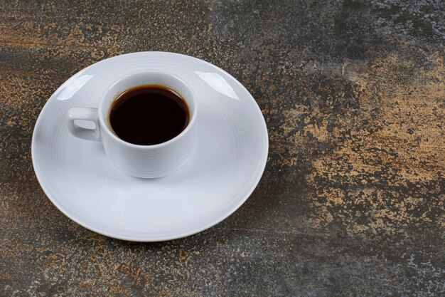 Taza de café negro sobre la superficie de mármol.