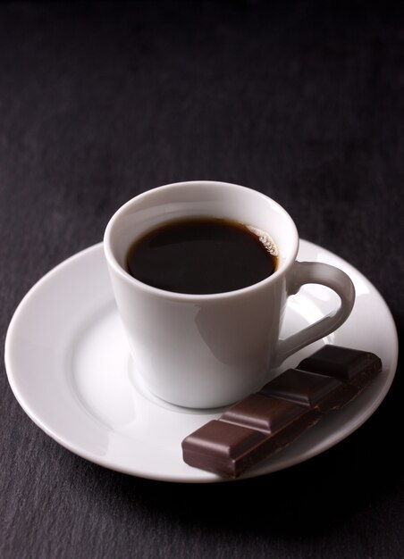 Taza de café negro con un trozo de chocolate