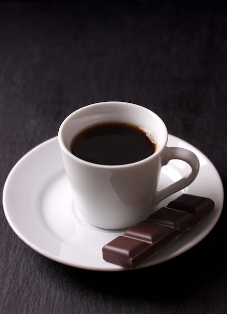 Taza de café negro con un trozo de chocolate