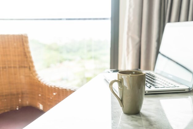 taza de café con ordenador portátil y hermosa decoración de mesa de lujo en el interior del salón de fondo