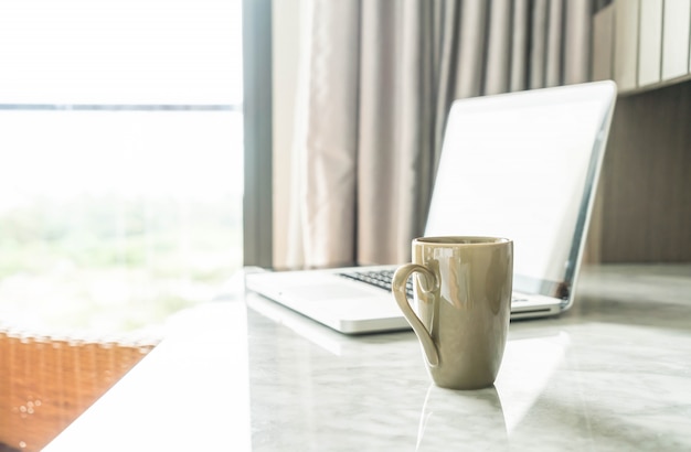 taza de café con ordenador portátil y hermosa decoración de mesa de lujo en el interior del salón de fondo