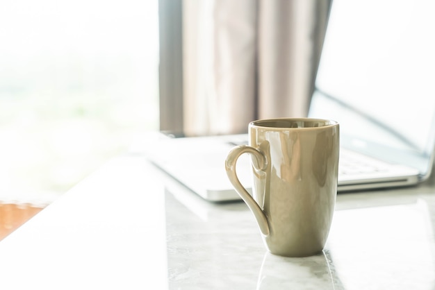 taza de café con ordenador portátil y hermosa decoración de mesa de lujo en el interior del salón de fondo