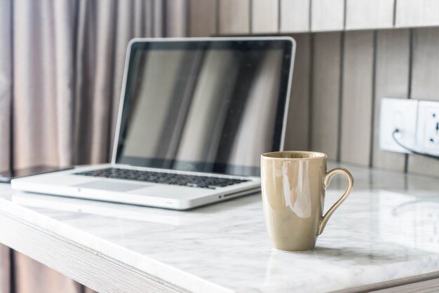 taza de café con ordenador portátil y hermosa decoración de mesa de lujo en el interior del salón de fondo