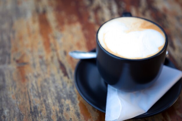 Taza de café oscura sobre una mesa de madera