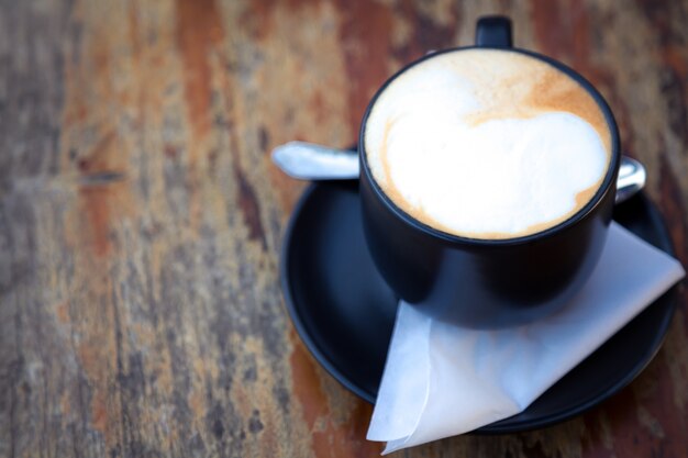 Taza de café oscura sobre una mesa de madera