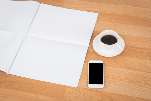 Taza de café con papeles en blanco y teléfono inteligente