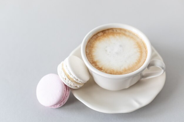 Taza de café, pasta para el pastel sobre un fondo gris y rosa. Copie el espacio.