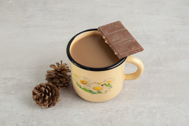 Taza de café con piñas y barra de chocolate.