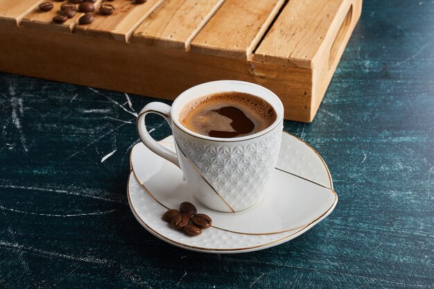 Una taza de café en platillo blanco.