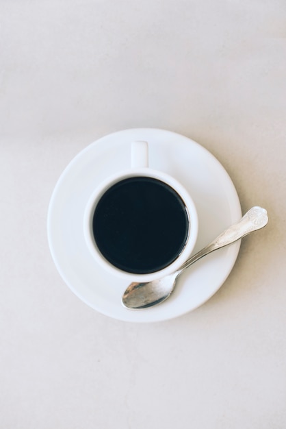 Taza de café y platillo con cuchara sobre fondo blanco