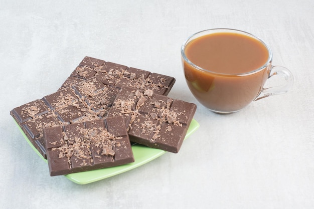 Taza de café y plato de barras de chocolate sobre fondo de piedra. Foto de alta calidad