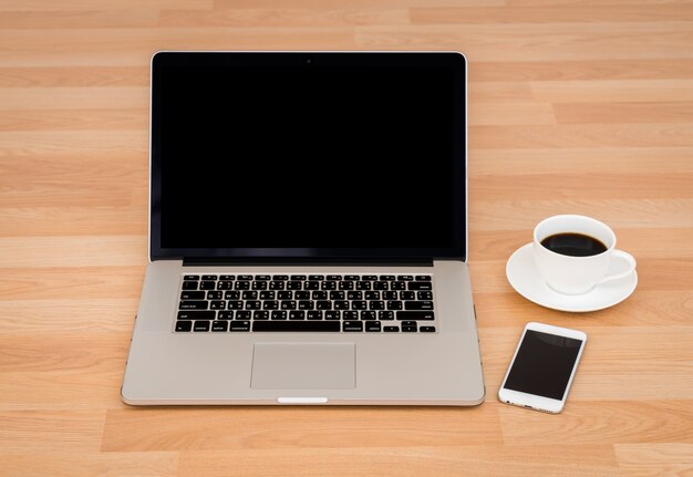 Taza de café con portátil y teléfono inteligente