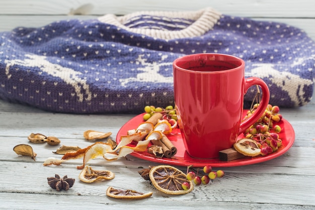 Taza de café roja en un plato, pared de madera, bebida