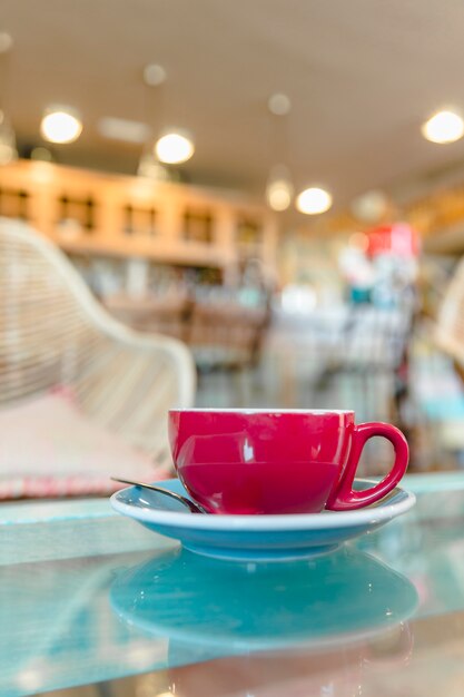 Taza de café rojo en el mostrador de vidrio en el café