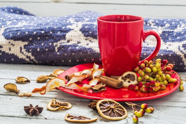 Taza de café rojo en un plato, mesa de madera, bebidas