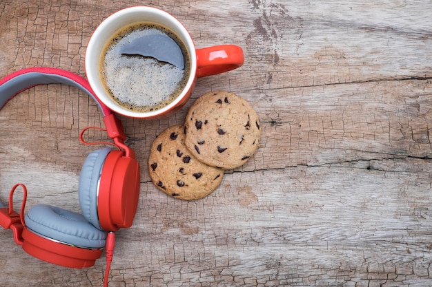 Taza de café rojo, rojo auriculares y galletas de chocolate en la mesa de madera. Vista desde arriba. Café con el concepto de chirstmas.